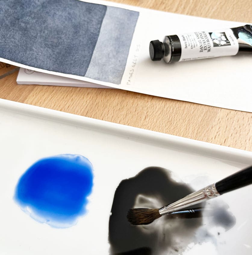 Paleta con un charco de azul ultramar y otro de negro junto a una muestra de gris de Payne